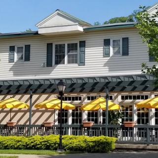 A restaurant with outdoor seating featuring yellow umbrellas and a white building facade on a sunny day.