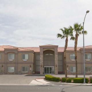 A hotel building with palm trees in front and a road leading up to it.