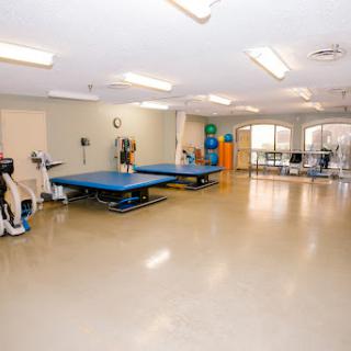 A spacious rehabilitation therapy room equipped with exercise tables and fitness gear.