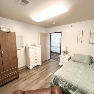 A cozy and neatly arranged bedroom featuring a bed, wardrobe, and dresser.