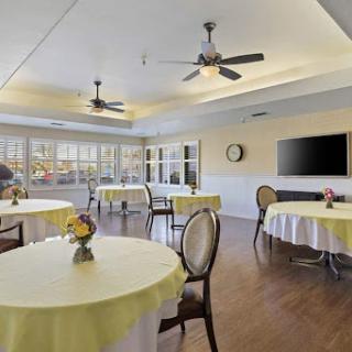 A bright and inviting dining area featuring tables with yellow tablecloths and ceiling fans, perfect for gatherings.