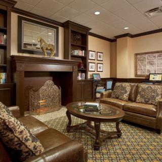 A cozy living room with a fireplace, sofas, and a coffee table, featuring classic interior design elements.