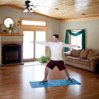 A person practicing yoga in a living room, performing a pose on a yoga mat.