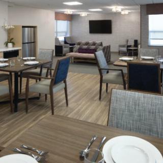 A modern dining area with neatly arranged tables and chairs, featuring wood flooring and a cozy atmosphere.