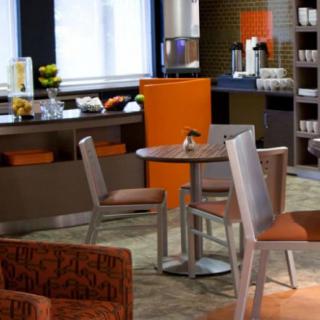 A modern cafe interior with tables and chairs, featuring a coffee station in the background.