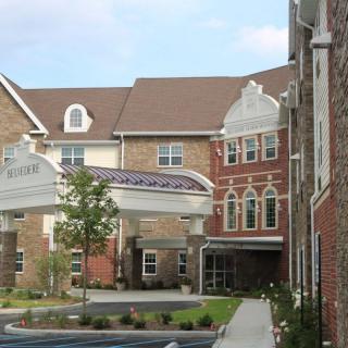 A view of a residential building with a covered entrance and landscaped surroundings.