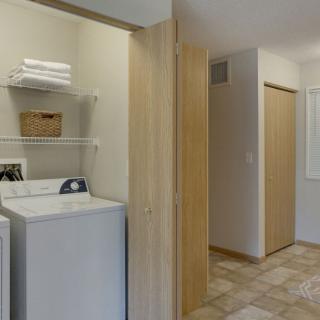 A laundry room featuring a washer and dryer with shelves above holding towels and a basket.