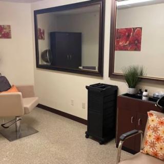 A cozy salon waiting area featuring comfortable chairs, large mirrors, and tasteful decor.