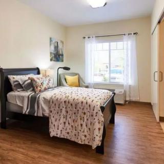 A cozy bedroom with a neatly made bed and a window letting in natural light.
