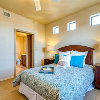 A cozy bedroom with a comfortable bed, colorful pillows, and warm lighting.