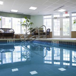 A serene indoor swimming pool area with natural light streaming through large windows.