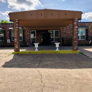 The welcoming entrance of a brick building under a beautiful cloudy sky.