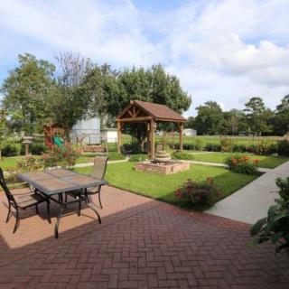A tranquil garden scene featuring a patio with outdoor furniture, a decorative well, and lush landscaping.