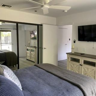 Modern bedroom interior with a wall-mounted TV and mirrored closet doors.