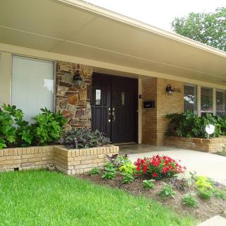 Front view of a house with landscaped garden and colorful flowers.