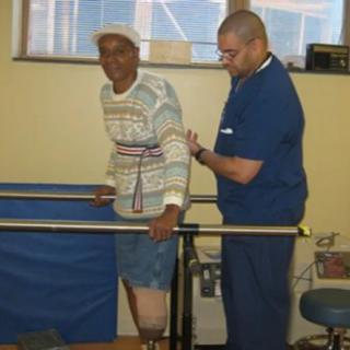 An elderly individual undergoes physical therapy with assistance from a healthcare professional.