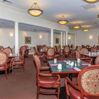 An elegantly decorated dining room with rows of tables and chairs, warmly lit by overhead lighting.