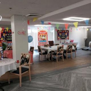 A brightly decorated indoor space set up for a party with colorful banners and arranged tables.