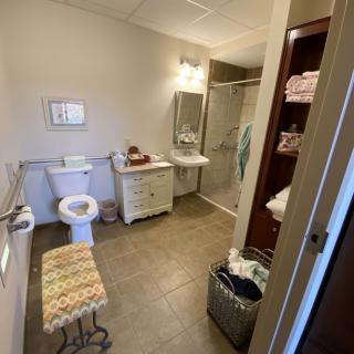 A spacious bathroom with a toilet, sink, and shower, featuring ample storage and a laundry basket.