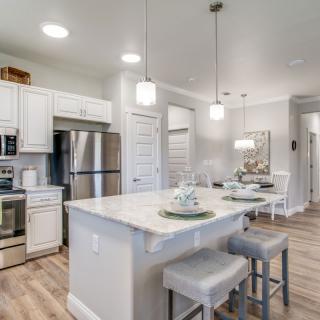 A modern kitchen with white cabinets, stainless steel appliances, and a central island with pendant lighting.