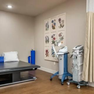 A clinical treatment room equipped with medical devices and a bed for patient care.