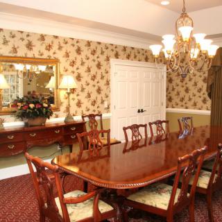 A classic dining room with a wooden table, elegant chairs, and a chandelier overhead.