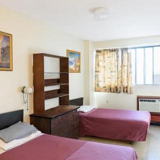 A cozy hotel room featuring two single beds, a wooden shelf, and artwork adorning the walls.