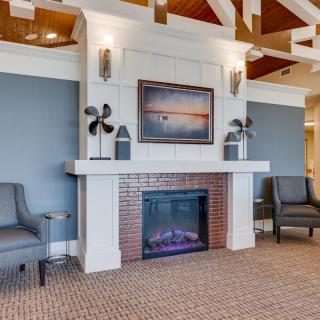 A cozy living room features a modern fireplace adorned with artwork and elegant armchairs.