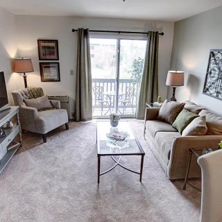 A cozy living room with a sofa, armchair, and coffee table, featuring a television and soft lighting.