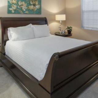 A neatly made bed in a warmly lit bedroom with modern furniture and decor.