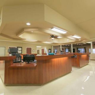 A spacious reception area with multiple desks and computers, illuminated by ceiling lights.