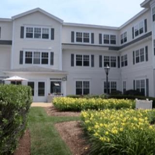 A multi-story residential building surrounded by a well-maintained garden.