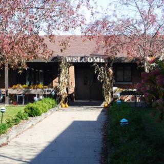 The entrance to a restaurant is adorned with seasonal decorations and surrounded by landscaped greenery.