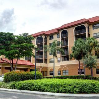 A multi-story residential apartment building surrounded by lush green landscaping.