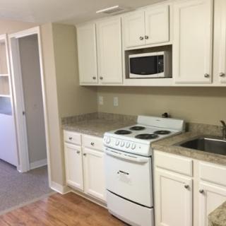 A modern kitchen with white cabinetry and essential cooking appliances.