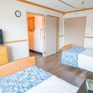 A cozy hotel room featuring two beds, a television, and simple decor.