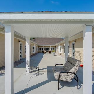 Outdoor patio area with seating under a pergola on a sunny day.