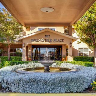 Entrance to a building with a central fountain surrounded by lush landscaping.