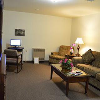 A cozy living room with a sofa, computer desk, and decorative flowers on the table.