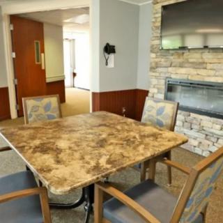 A cozy dining area featuring a stone fireplace and a television mounted above it.
