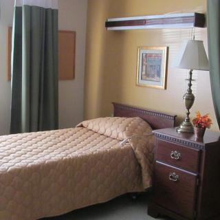 A neatly arranged hospital room with a single bed and nightstand.
