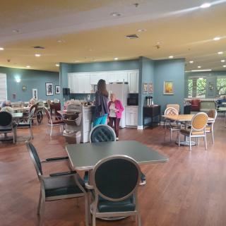 A modern cafe with tables and chairs, where people are interacting near the counter.