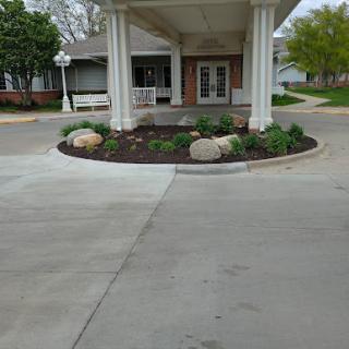 An inviting entrance to a building, featuring landscaped gardens and smooth concrete pathways.