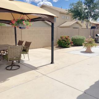 A sunny backyard patio with a table and chairs under a large umbrella.