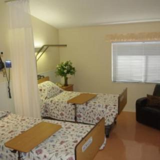 A hospital room with two patient beds, equipped with medical monitoring devices and curtain dividers.