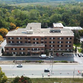 Aerial view of a hospital building surrounded by greenery and a road.
