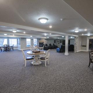Spacious basement area with seating and tables, well-lit with ceiling lights.