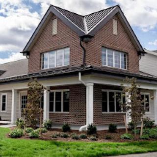 A beautifully designed two-story brick house with a well-maintained garden.