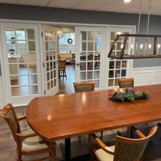 A stylish dining room with a wooden table and chairs, featuring glass doors and modern lighting.