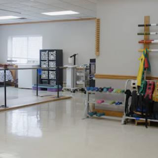A bright and spacious physical therapy room equipped with various exercise tools.